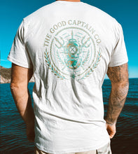 Load image into Gallery viewer, Silver Tee with the Good Captain Co emblem printed on the back in gold and turquoise
